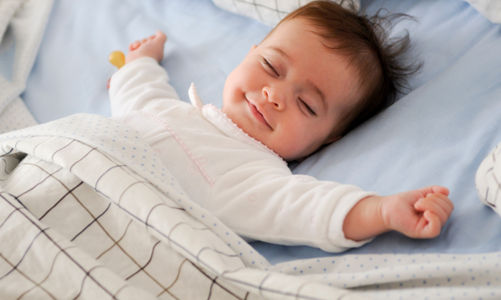 A baby peacefully sleeping in a bed, covered with cozy linen textiles blankets