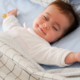 A baby peacefully sleeping in a bed, covered with cozy linen textiles blankets