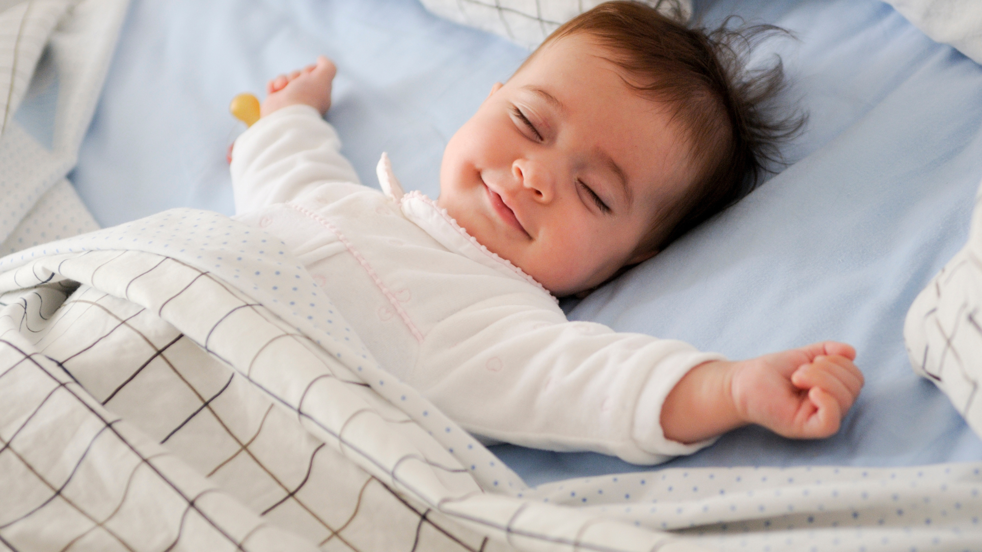 A baby peacefully sleeping in a bed, covered with cozy linen textiles blankets